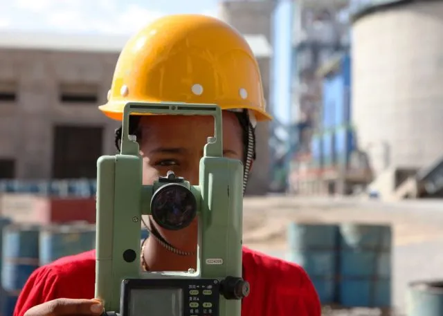 Person wearing a yellow hard hat holding a camera