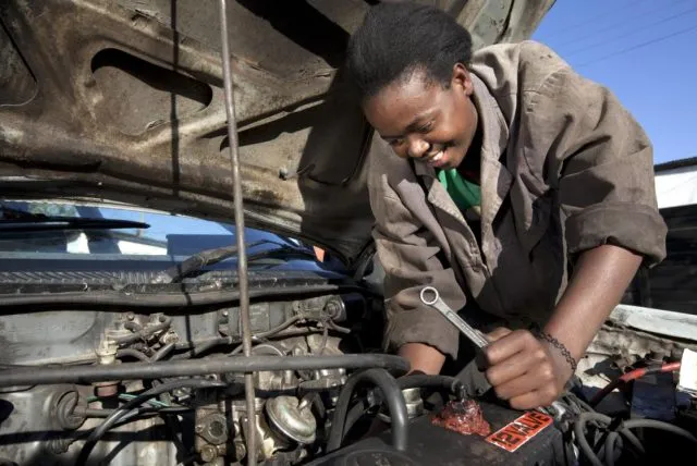 African woman working on car