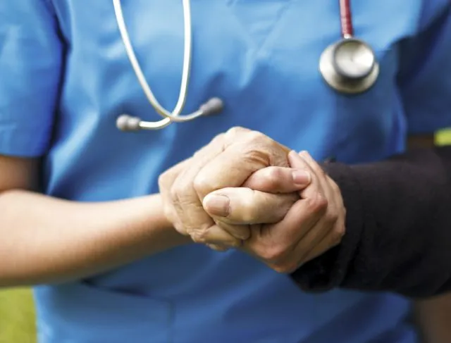 A nurse holding an elderly hand