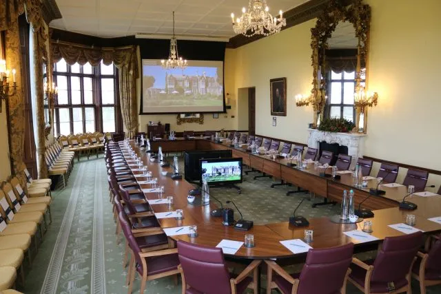 Wilton Park's conference room with table, chairs, project screen and monitor