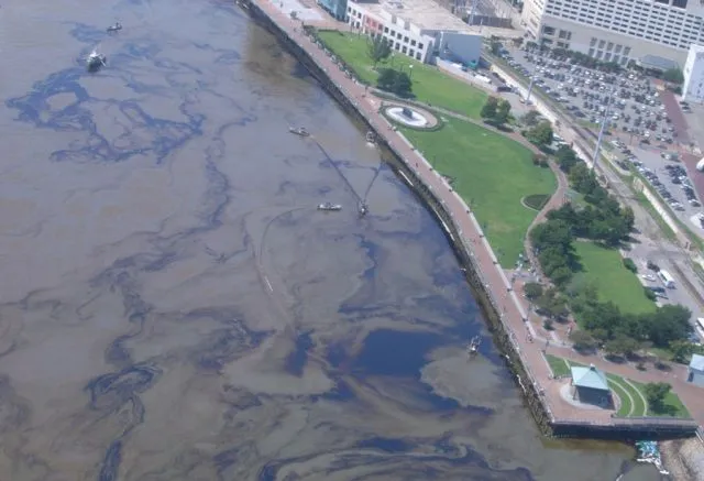 Oil spill in the sea by a city shoreline