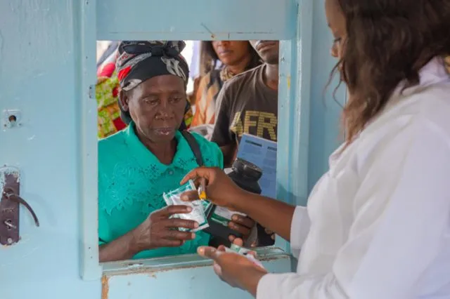 A doctor giving out HIV treatment out of window to a que of people in Zambia
