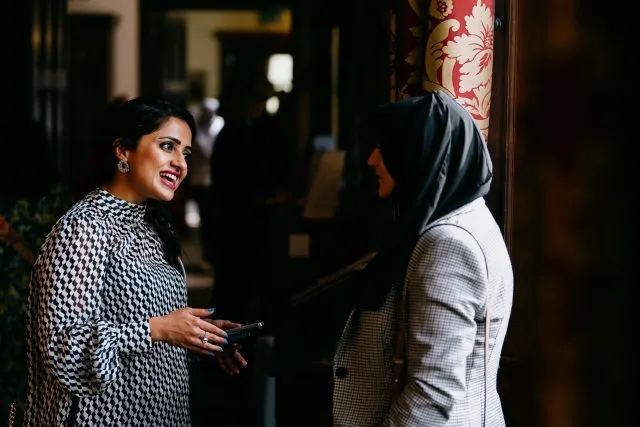 Two participants in conversation during a break at a Wilton Park event at Wiston House.