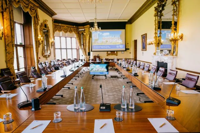 The conference table at Wilton Park is set up for a meeting with water, paper and pens laid out.