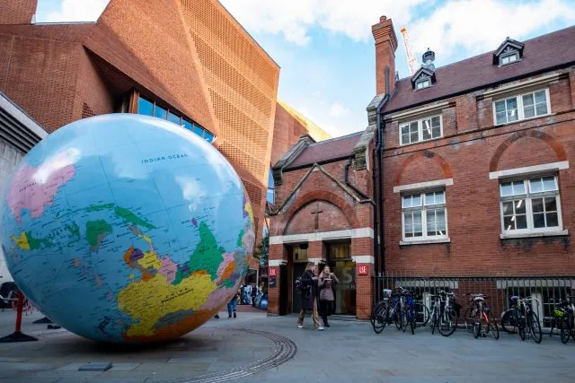 A large model of the globe stands in a courtyard between buildings at the London School of Economics